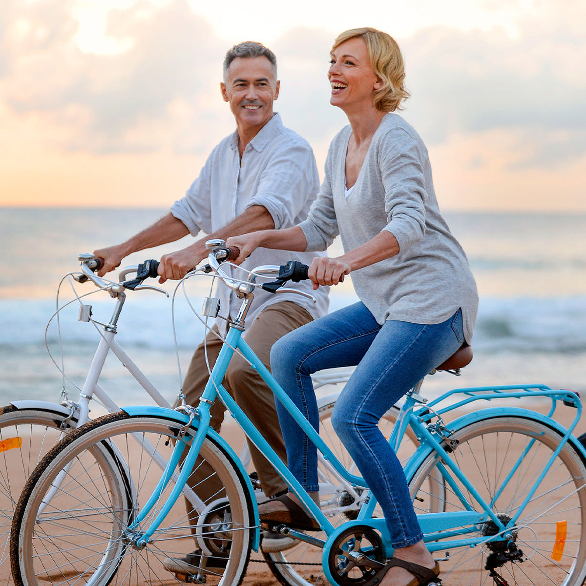 Right, Happy Husband and Wife riding blue bikes on the beach.