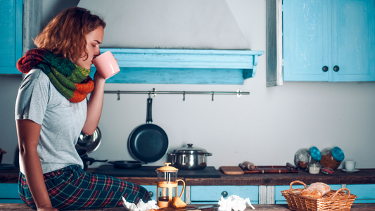 Woman sitting on kitchen counter, drinking from a mug