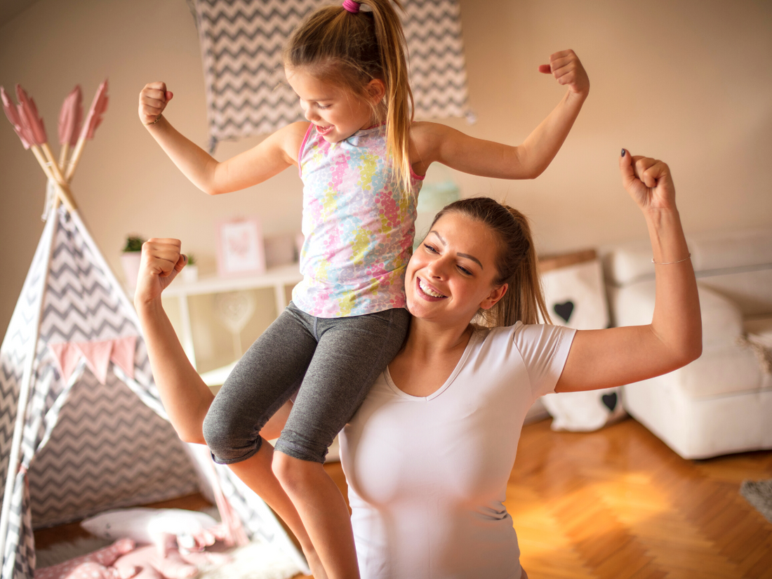 Woman with her daughter on her shoulder, both flexing their muscles